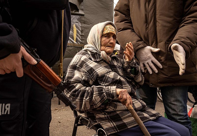 Una mujer es asistida por la policía tras huir de su casa en los suburbios de Kiev, durante la guerra en Ucrania.