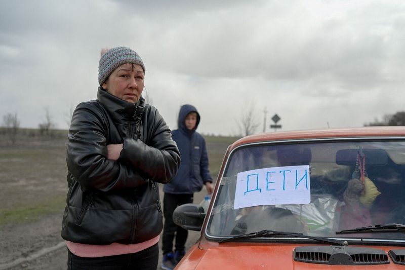 Una mujer junto a un coche averiado con un cartel de "niños" pegado en el parabrisas delantero, en las afueras de Mykolaiv, una ciudad clave en el camino a Odesa, el mayor puerto de Ucrania.