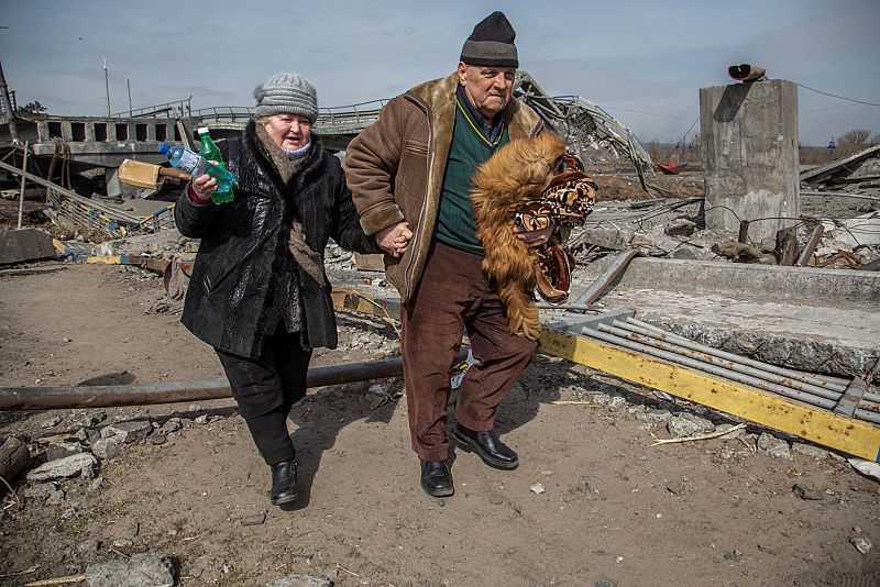 Una pareja de ancianos camina junto a un puente destruido durante la evacuación de la ciudad de Irpin