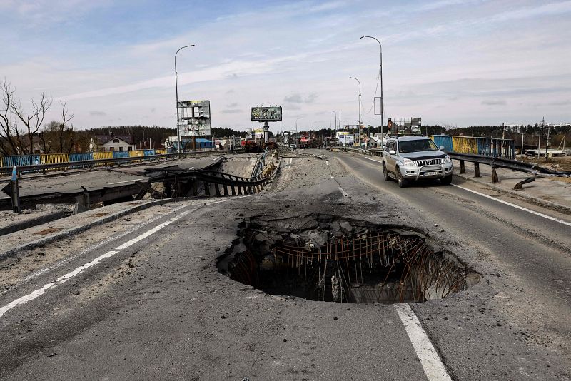 Un vehículo pasa al lado de un agujero en un puente dañado, en las afueras de Kiev. 