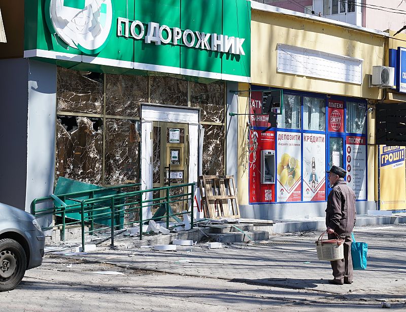 Un hombre espera frente a la fachada de un antiguo banco por las calles de Mykolaiv.