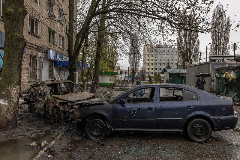 Personas junto a coches destruidos en la zona residencial afectada por los bombardeos de la artillería rusa, en Járkov