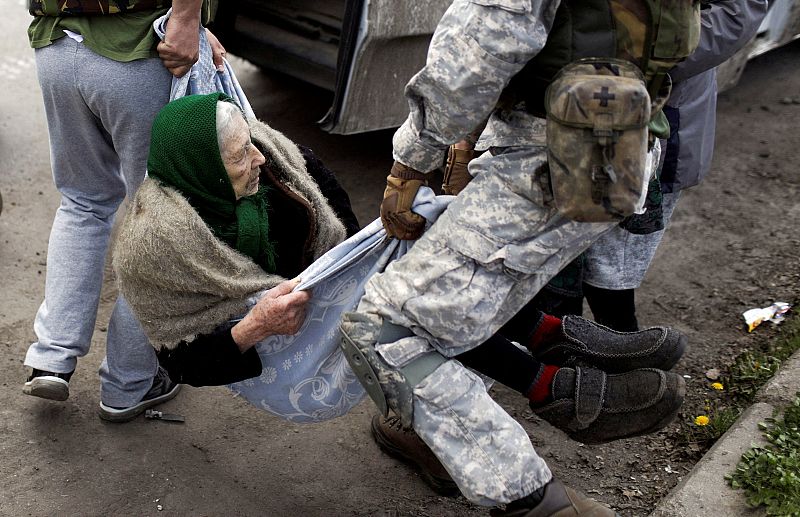 Voluntarios llevan a una anciana después de evacuar a los residentes de un pueblo retomado por las fuerzas ucranianas, junto a una línea del frente, en medio de la invasión rusa de Ucrania, en Járkov.