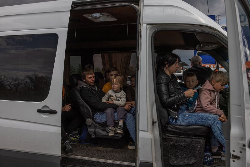 Desplazados internos de las zonas ocupadas por Rusia en el sur de Ucrania sentados en un monovolumen tras llegar al punto de evacuación en Zaporiyia