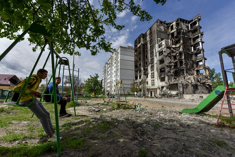 Dos niños sentados en un columpio en el patio de un edificio de apartamentos destruido por un ataque aéreo, en Borodyanka, en las afueras de Kiev