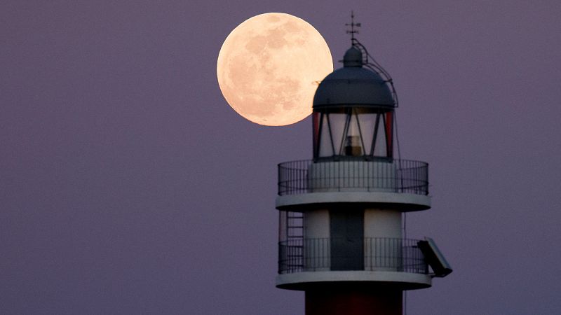 La luna llena asoma tras el faro de Arinaga, en la isla de Gran Canaria.