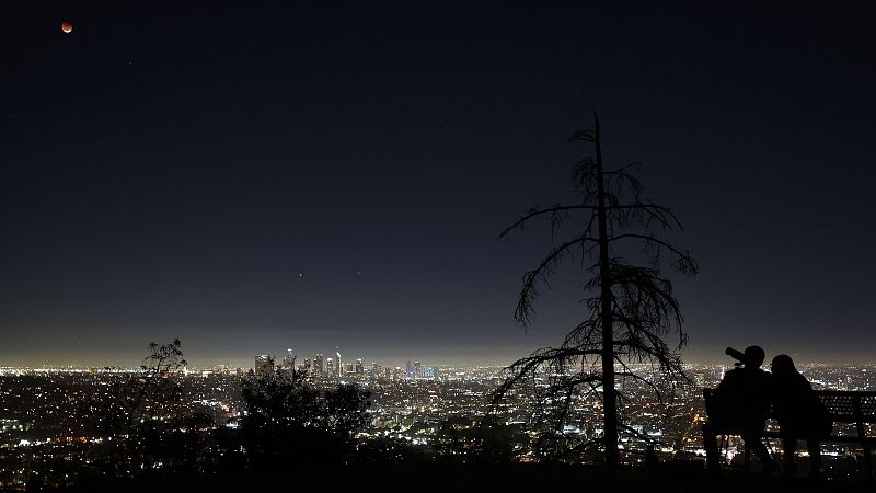 Dos personas observan el eclipse desde Griffith Park, en Los Ángeles, California.