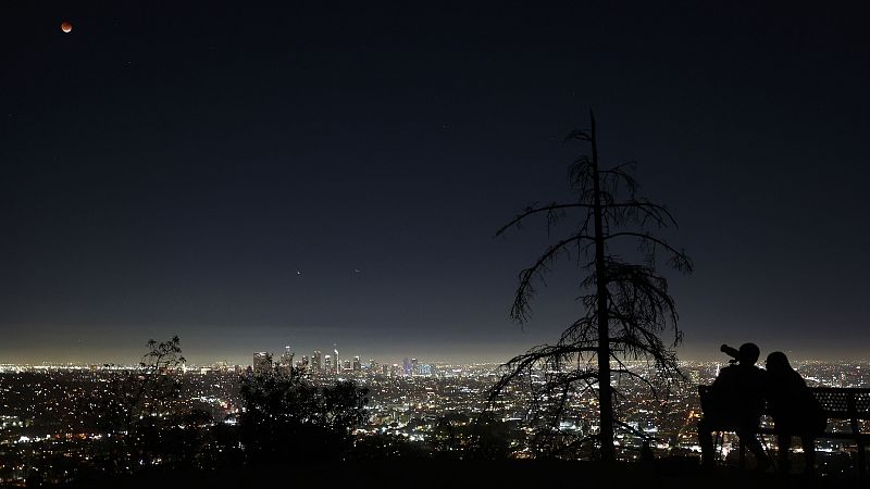 Dos personas observan el eclipse desde Griffith Park, en Los Ángeles, California.