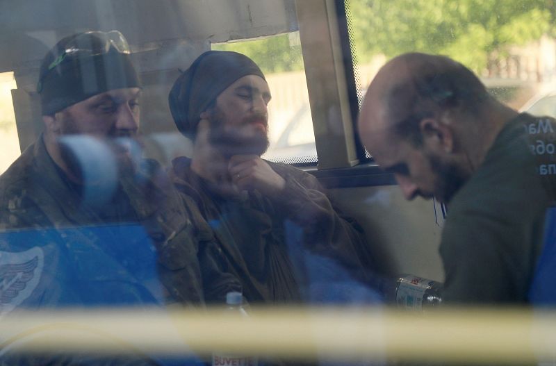 Los miembros de las fuerzas ucranianas que se han rendido después de semanas encerrados en la planta siderúrgica de Azovstal son vistos dentro de un autobús, que ha llegado escoltado por los militares prorrusos a un centro de detención en el curso de