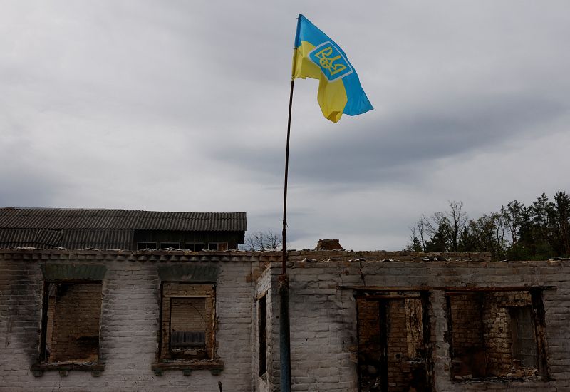 Una bandera ucraniana se ve fuera de una casa destruida, mientras los aldeanos regresan a la aldea de Moshchun, en Kiev.