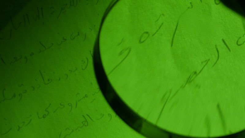 una lupa estudia un texto en árabe