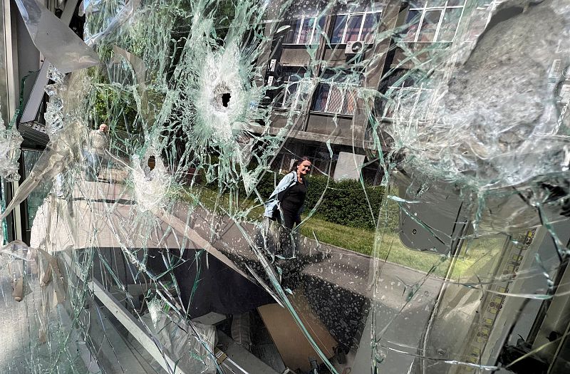 Un edificio se refleja en un escaparate en una zona residencial tras un bombardeo con munición de racimo, mientras continúa el ataque de Rusia a Ucrania, en Járkov.