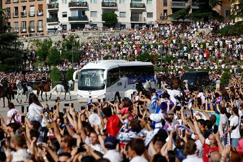 Miles de aficionados escoltan al atubús del Real Madrid en las calles de la capital de España.