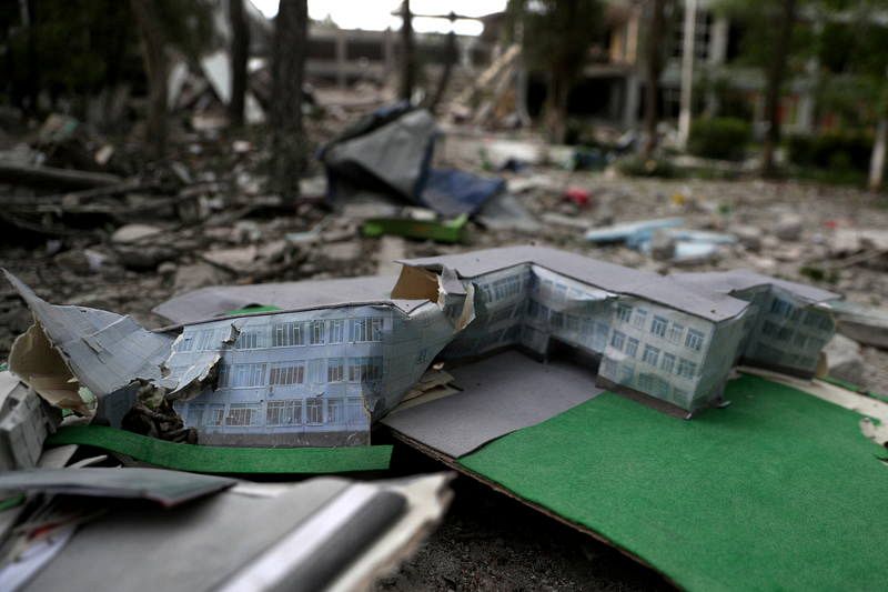 Una maqueta de una escuela se ve rota delante de la propia escuela dañada después de un ataque con misiles, en medio del ataque de Rusia a Ucrania, en una zona residencial en Járkov.