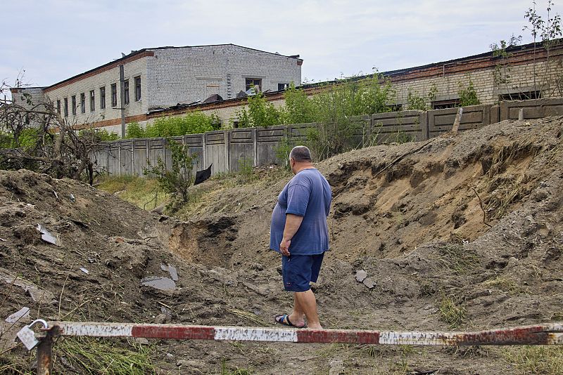 Un lugareño observa un agujero de bombardeo tras un reciente ataque con cohetes contra una fábrica de madera en las afueras de la pequeña ciudad de Bezlyudovka, en la zona de Járkov