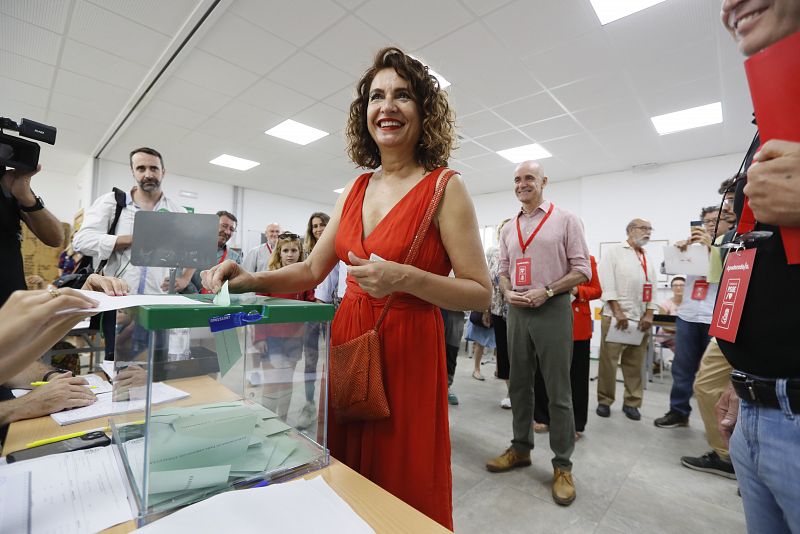 La ministra de Hacienda, María Jesús Montero, acompañada por el alcalde de Sevilla, Antonio Muñoz (detrás), en el momento de introducir el sobre con su papeleta en la urna en el colegio electoral de la SAFA de Sevilla