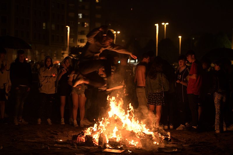 Un joven salta una hoguera durante la noche de San Juan en la playa de Poniente, en Gijón. 