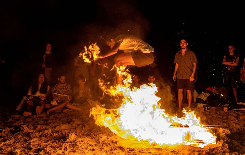 Un hombre salta sobre una hoguera durante las celebraciones de San Juan en una playa de Alicante. 