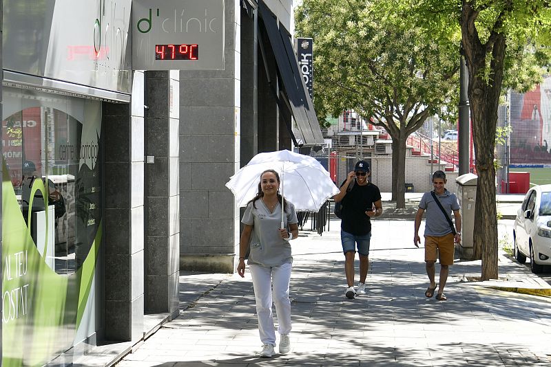 Una mujer pasa por una farmacia cuyo termómetro marca 47º en una calle del centro de Lleida