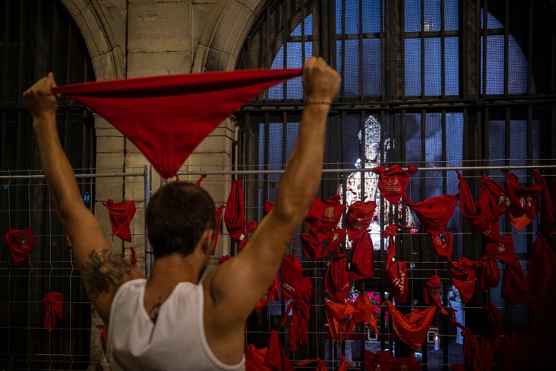 Un corredor ofrece su pañuelo rojo a la figura de San Fermín, marcando el final de las fiestas en Pamplona