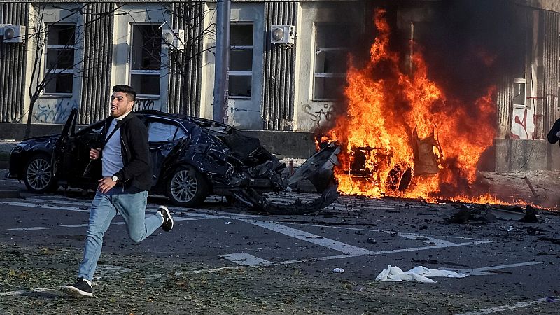Una persona corre por la calle del centro de Kiev mientras un coche alcanzado por los bombardeos arde en segundo plano. REUTERS/Gleb Garanich