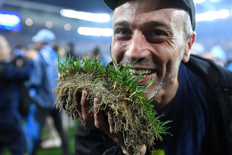 Un aficionado del Nápoles posa con un trozo de césped del campo del Udinese tras la consecución del título de Liga por su equipo.