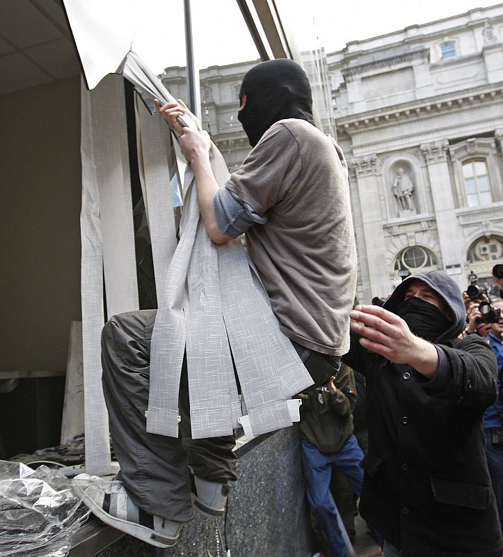 Un protestante entra en una sucursal del Royal Bank of Scotland por el escaparate roto.