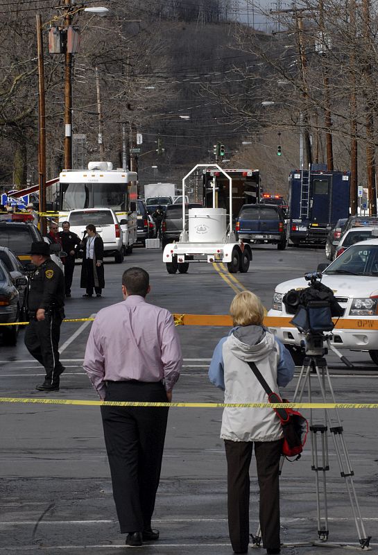 Members of the media watch police investigate a shooting scene outside the American Civic Center on Front Street in Binghampton