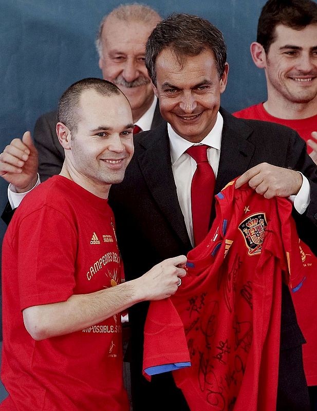 El presidente del Gobierno de España, José Luis Rodríguez Zapatero, posa con una camiseta firmada por los jugadores junto al centrocampista Andrés Iniesta.