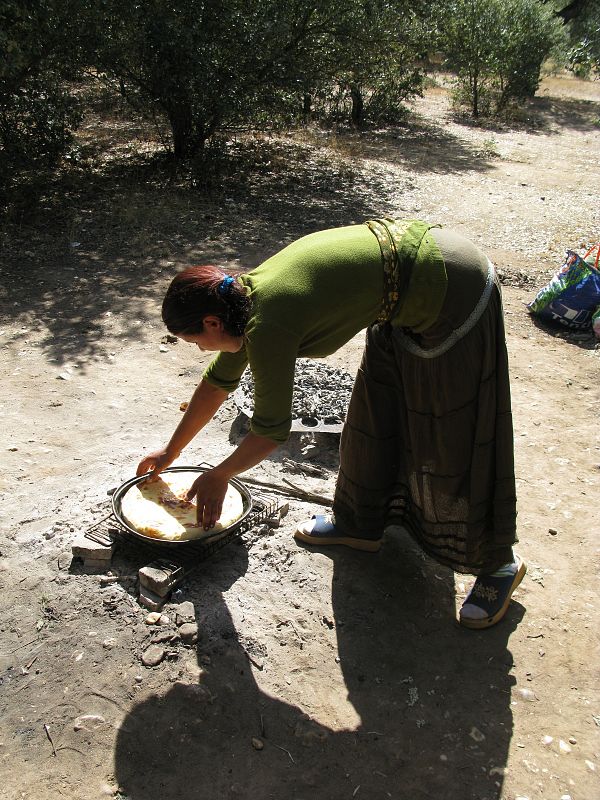 Una mujer rumana del campamento de Villoria le da la vuelta a la torta de pan.