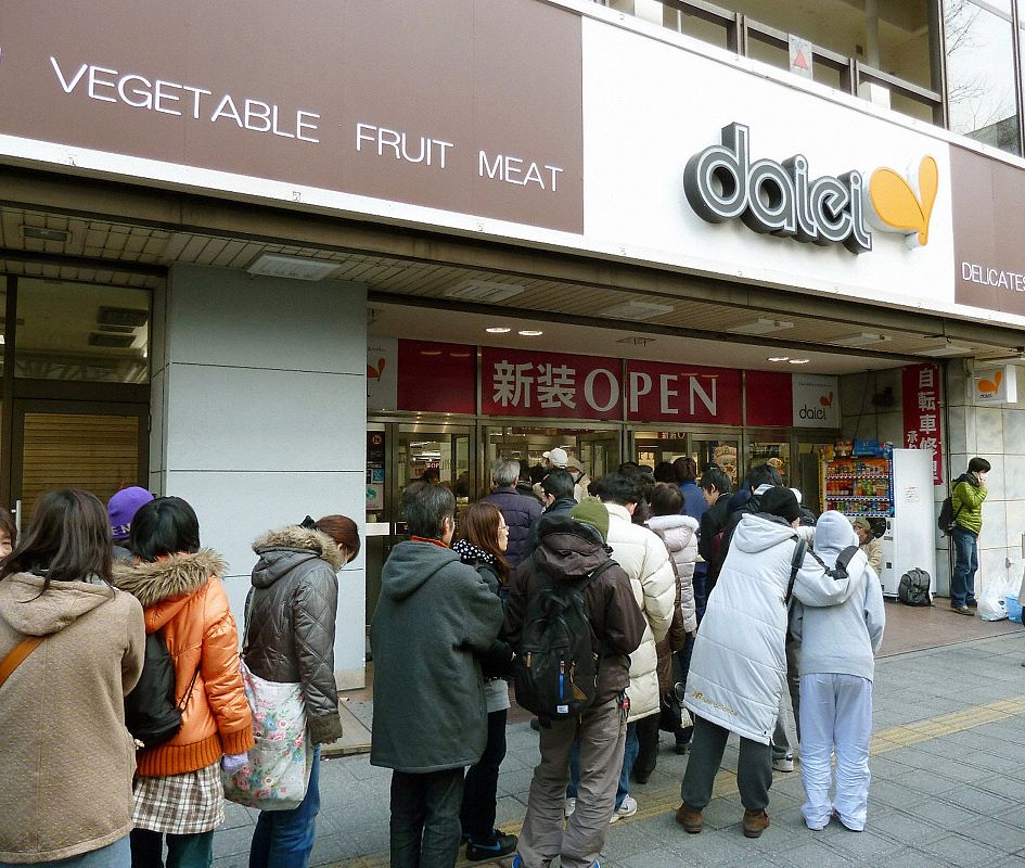 People wait in line to get food in front of a supermarket after a magnitude 8.9 earthquake and tsunami hit Sendai City
