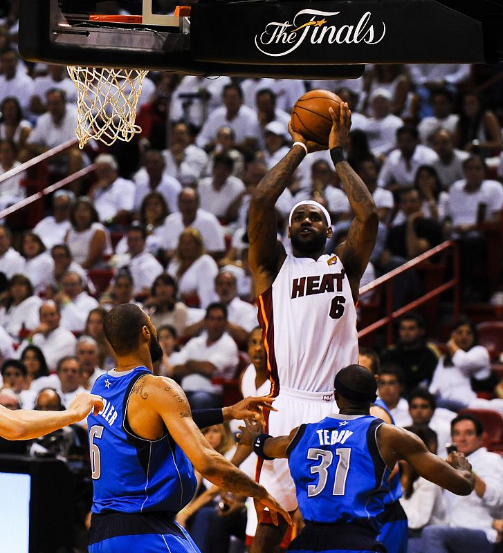 El jugador de los Heat de Miami LeBron James (C) anota sobre la marca de los jugadores de los Mavericks de Dallas Tyson Chandler (i) y Jason Terry (d) durante el sexto juego de la final de la NBA.