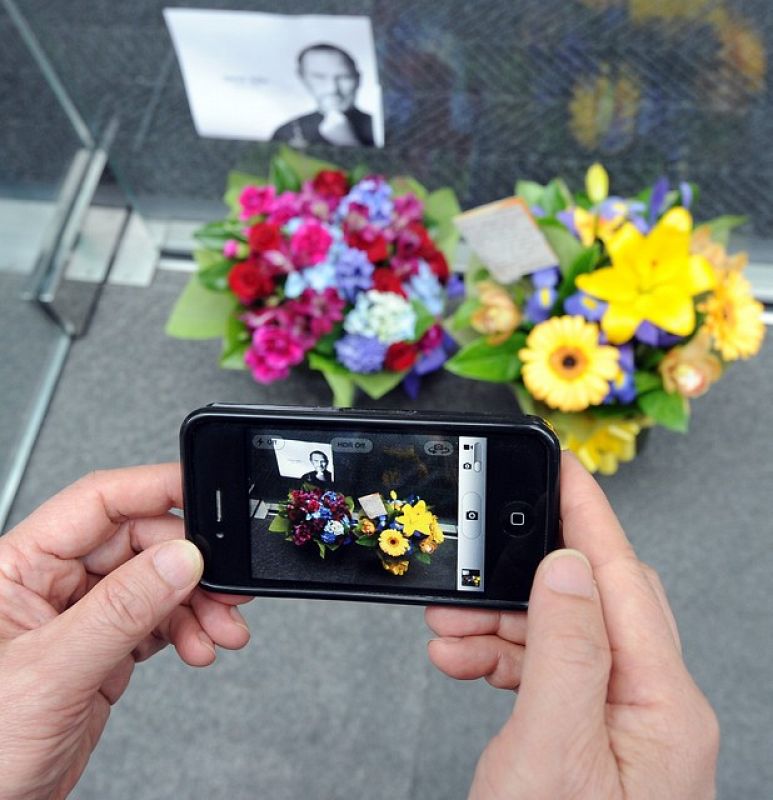 Un australiano hace una foto a las flores depositadas para homenajear a Steve Jobs con un iPhone, una de sus creaciones