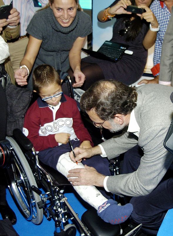 Mariano Rajoy firma en la escayola de un niño durante el mitin de Badajoz