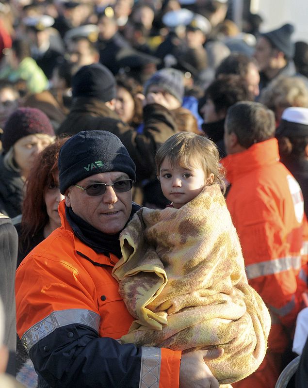 A rescue worker carries child as they arrive at Porto Santo Stefano after cruise ship ran aground off west coast of Italy at Giglio island