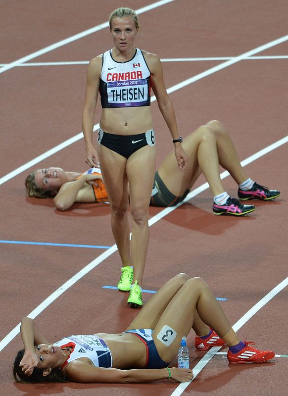 La canadiense Brianne Theisen camina entre varias compañeras exhaustas tras finalizar el heptatlón femenino.