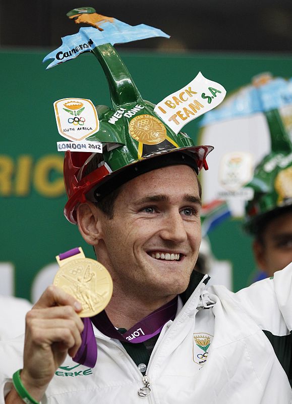 El nadador sudafricano Cameron van der Burgh que consiguió el oro olímpico muestra su medalla a los aficionados durante su llegada a el Aeropuerto Internacional OR Tambo de Johannesburgo.