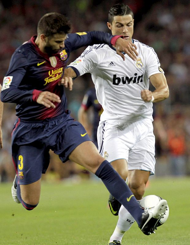 El delantero portugués del Real Madrid, Cristiano Ronaldo , lucha el balón con Gerard Piqué, del FC Barcelona, en el Camp Nou,