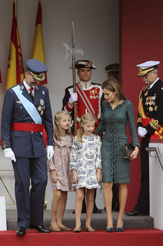 Los reyes, junto a sus hijas, la princesa de Asturias y la infanta Sofía, abandonan la tribuna de autoridades al término del desfile militar que han presidido.