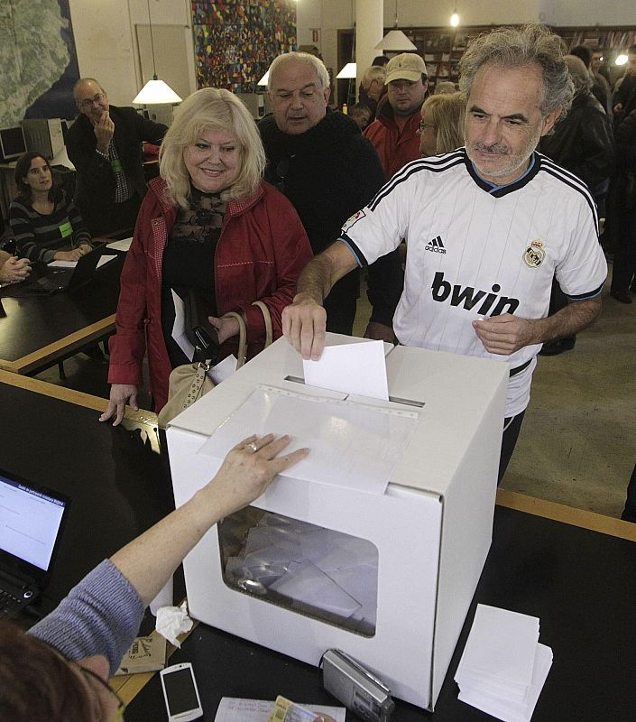Un ciudadano, vestido con la camiseta del Real Madrid, deposita su papeleta en el Institut Montserrat de Barcelona.
