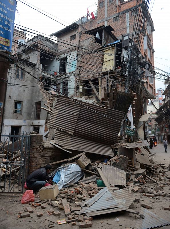 Un hombre, parte inferior izquierda, mira a través de los escombros tras el terremoto que ha dejado más de 800 muertos.