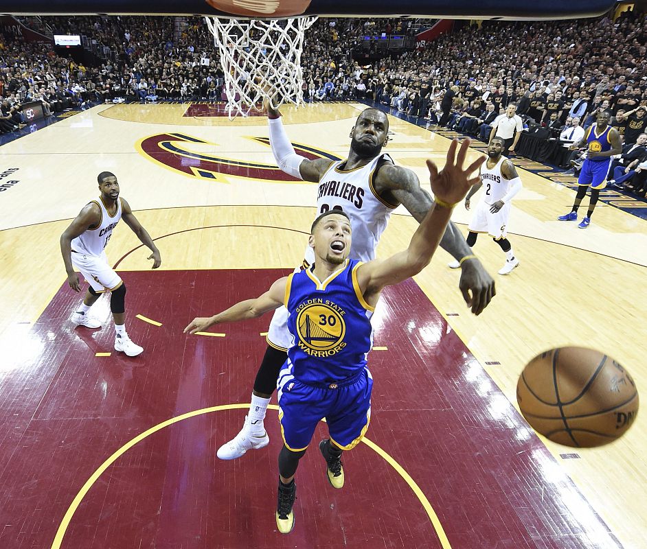 El jugador de los Warriors Stephen Curry (en primer plano) lucha por el balón con LeBron James (atrás) de los Cavaliers (16 de junio de 2016)