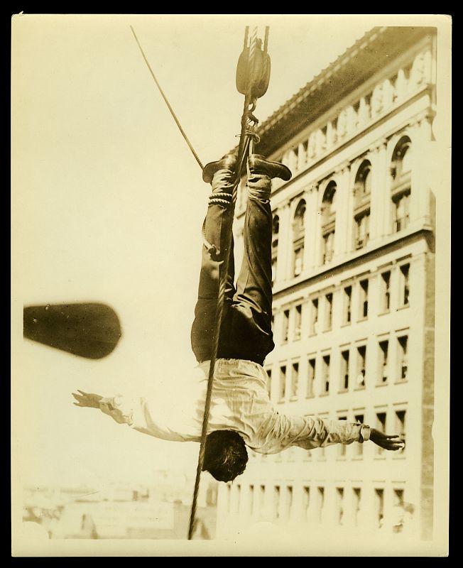 Houdini haciendo un número de escapismo suspendido de una grúa (McCord Museum)