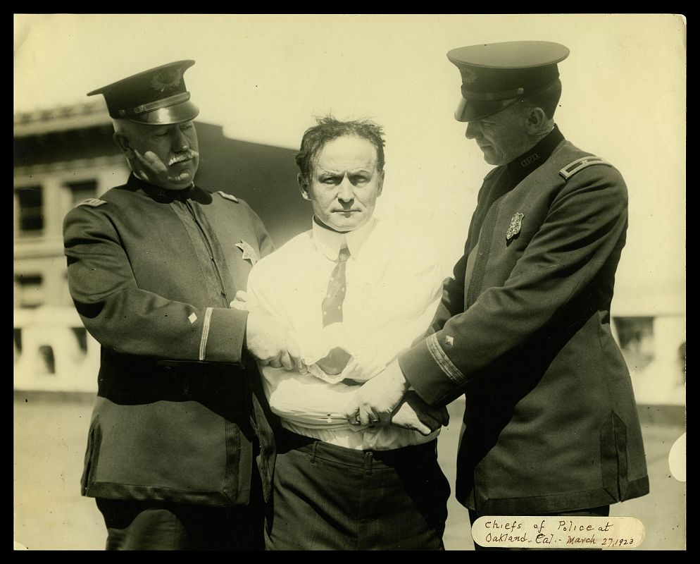 Houdini sujeto por dos oficiales de Policía en un truco en 1923 (McCord Museum)