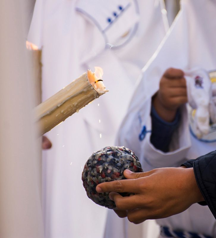 Un niño pide cera para su bola a un nazareno de la Hermandad de la Resurrección de Sevilla