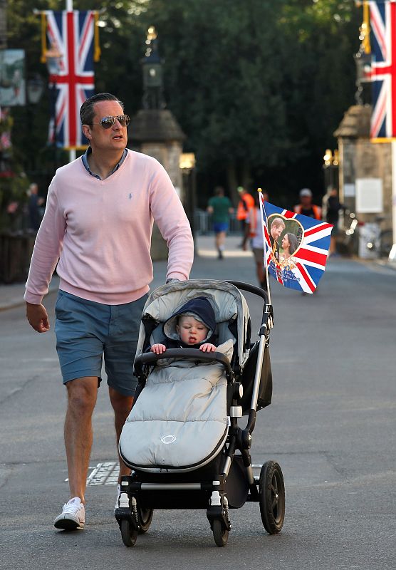 A man pushes a baby in a pushchair throught the centre of Windsor on the day before the wedding of Britain's Prince Harry and Meghan Markle in Windsor