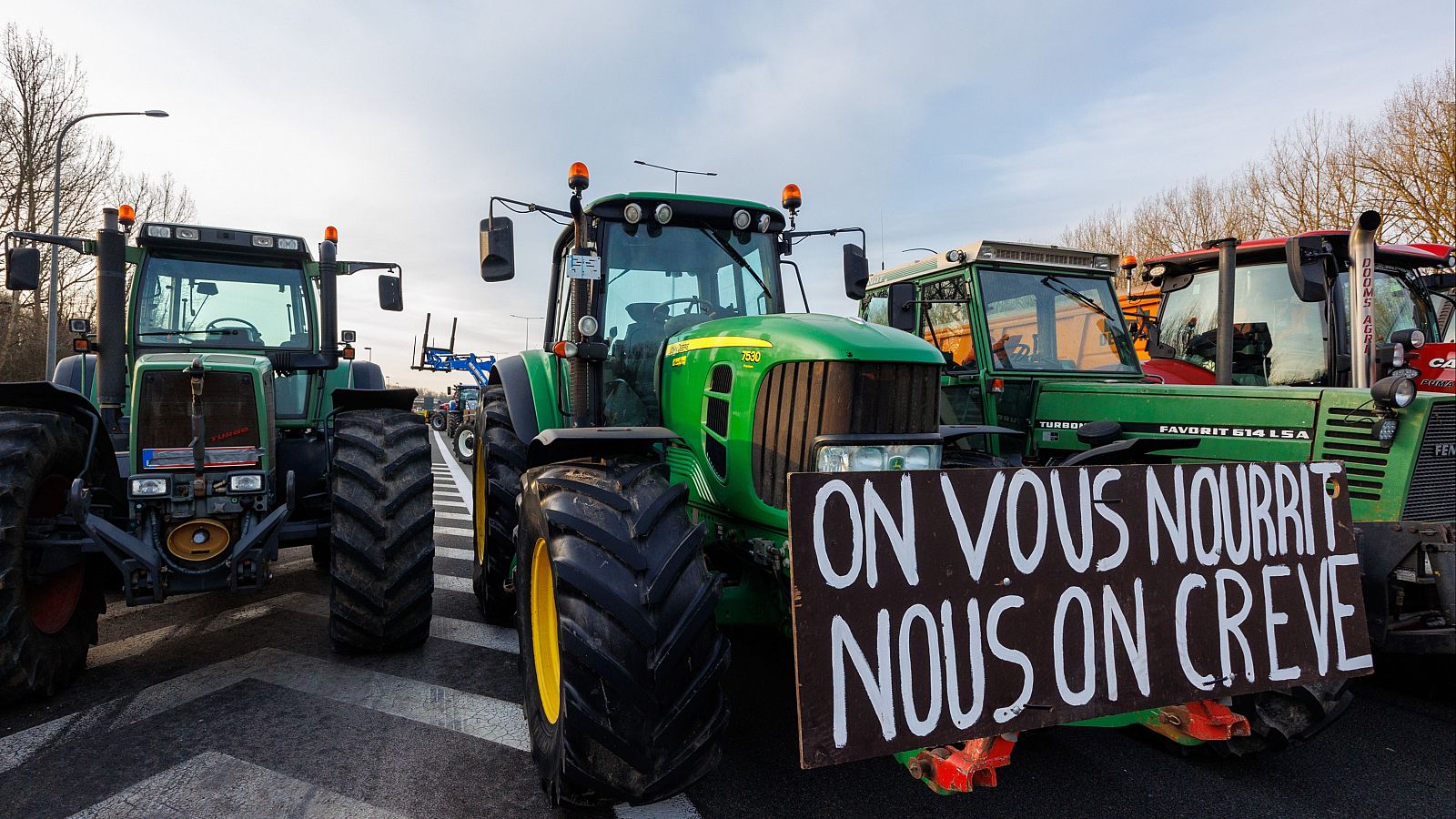 Durante las movilizaciones, un tractor sostiene una pancarta donde puede leerse "nos morimos de hambre mientras os alimentamos"