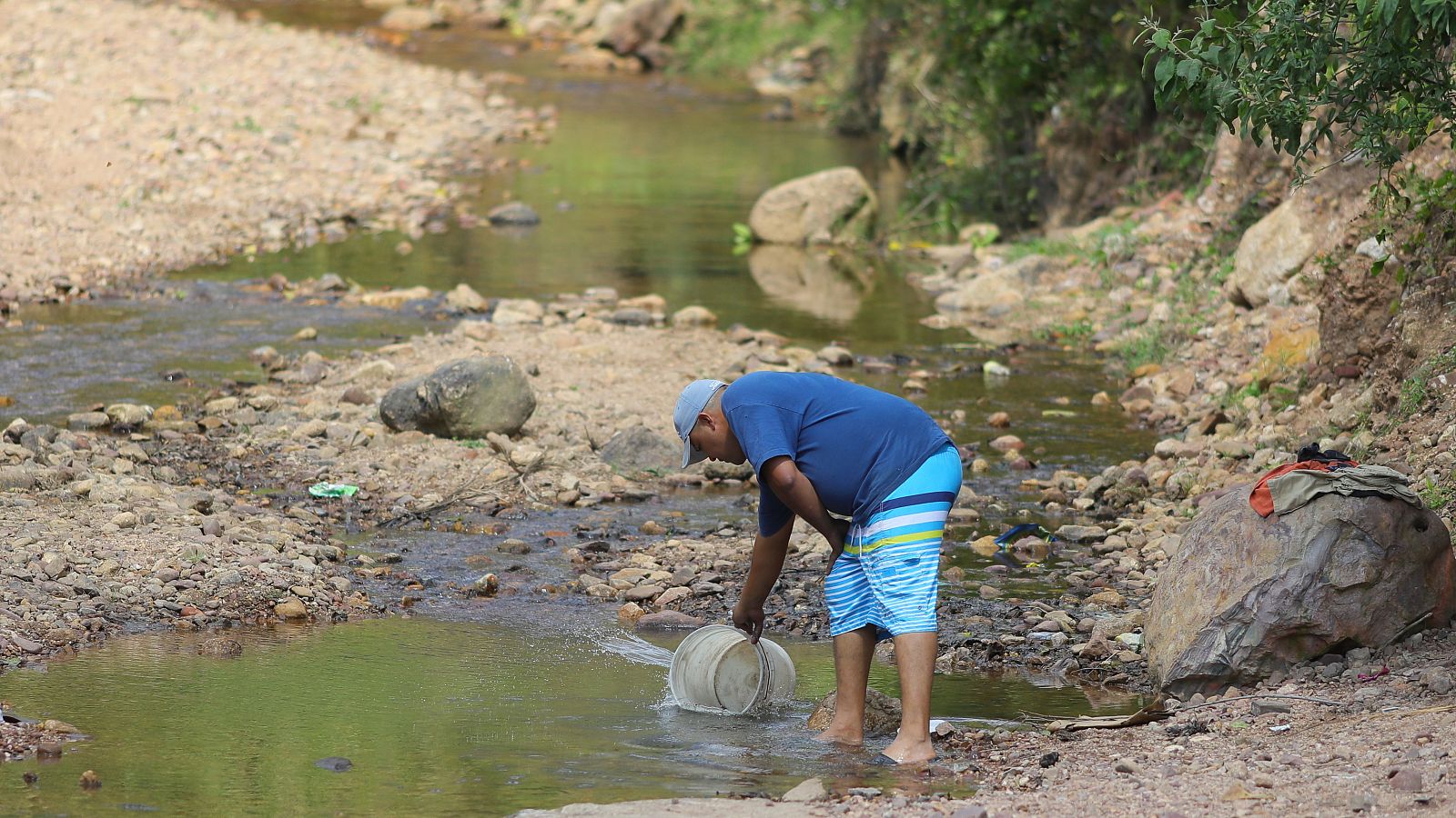 Un hombre recoge agua de una quebrada para combatir las altas temperaturas, el 4 de febrero de 2024, en una quebrada en el municipio de Valle de Ángeles, en el departamento de Francisco Morazán (Honduras).