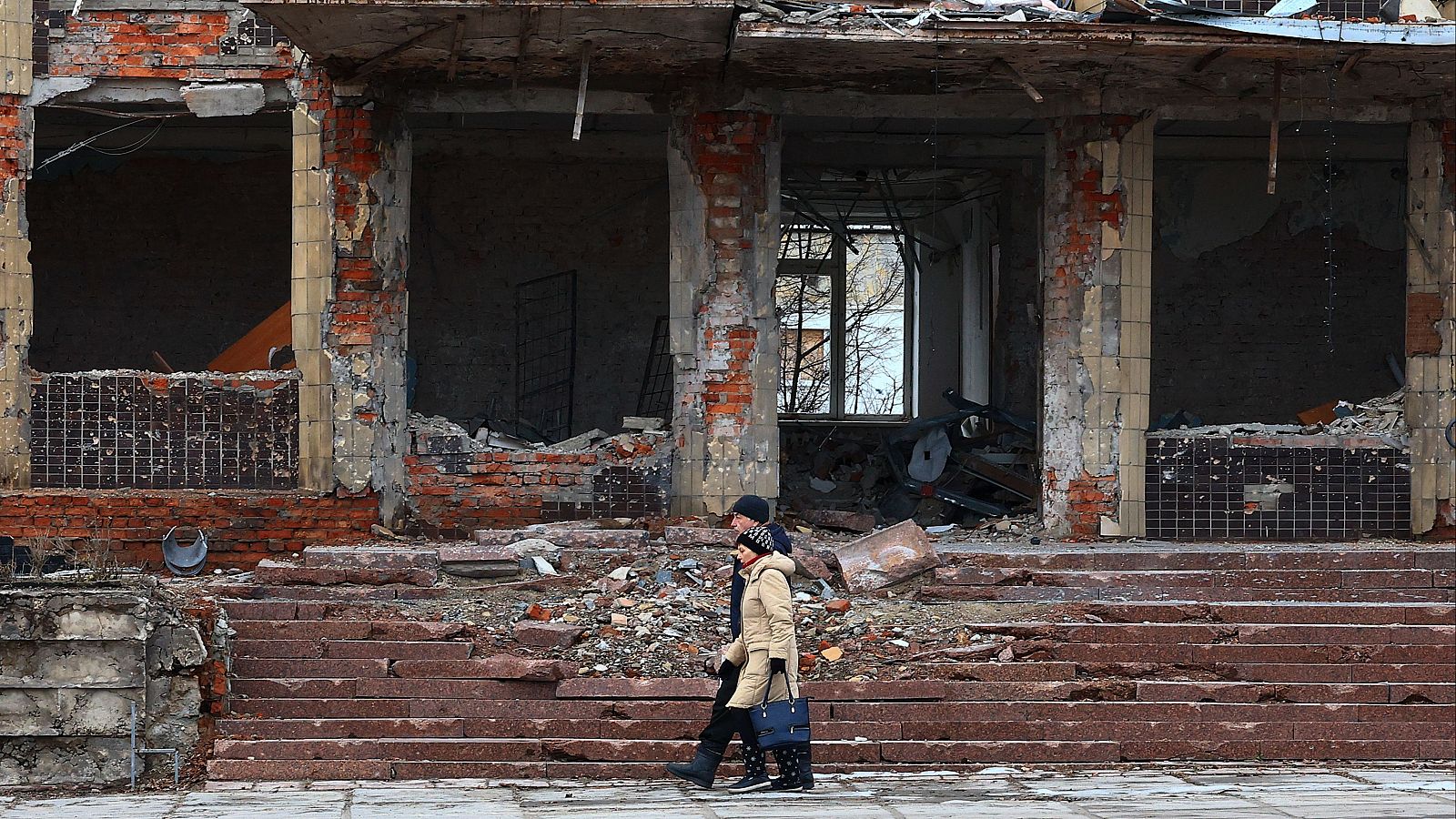 Una pareja camina cerca de los escombros de edificios destruidos en Kupiansk