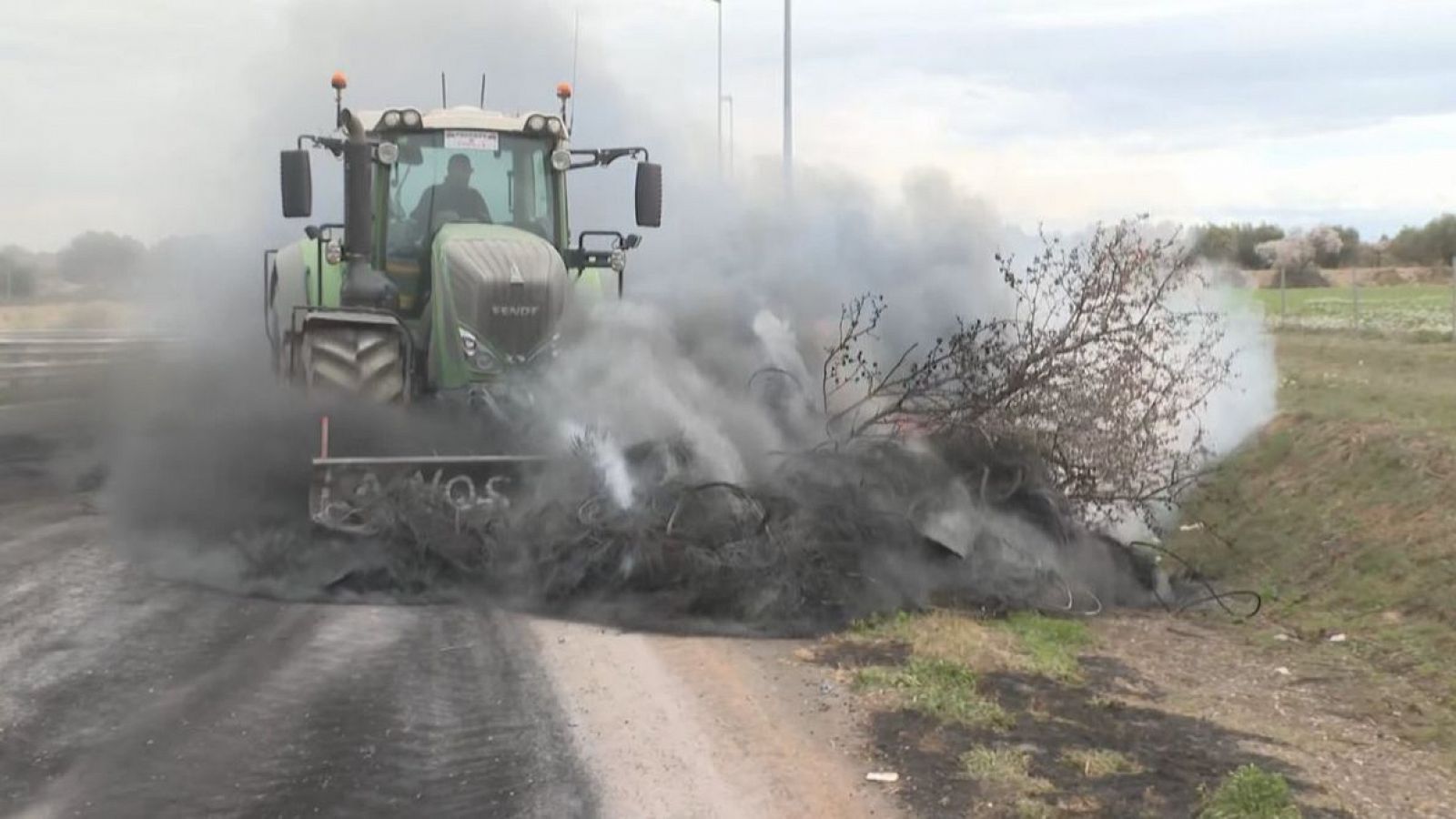 Un tractor retira de la calçada restes cremades de la protesta a l'A-2 que s'ha allargat 5 dies